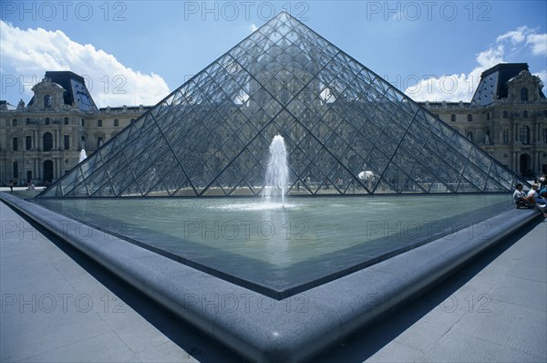 FRANCE, Ile De France, Paris, Louvre art gallery with a symetrical view of the Pyramid and fountain in the foreground