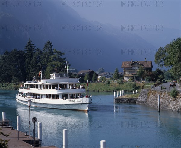 SWITZERLAND, Bern Oberland, Interlaken, White passenger ferry nearing quay with misty wooded mountains in the distance