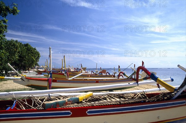 INDONESIA, Bali, Sanur Beach, View over row of colourful Outrigger fishing boats on the Beach