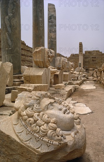 LIBYA , Leptis Magna, Roman ruins of the New Forum with carved face in the foreground and green marble pillars behind