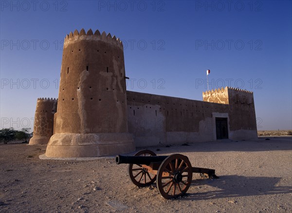 QATAR, Zubara, "Exterior view of a fort with crenellated towers, built in 1938 and used as a police border post, now a museum.  A cannon in the foreground.   "