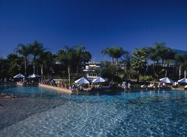 USA, Florida,  Orlando , Seaworld. View across a pool towards visitors gathered along the edge near sun shades