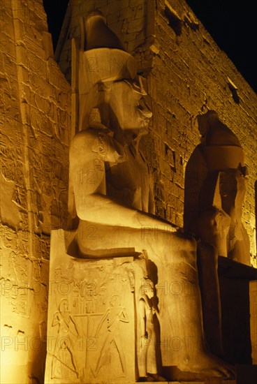 EGYPT, Luxor, The temple illuminated at night with the giant statues of Ramesses II outside The Pylon