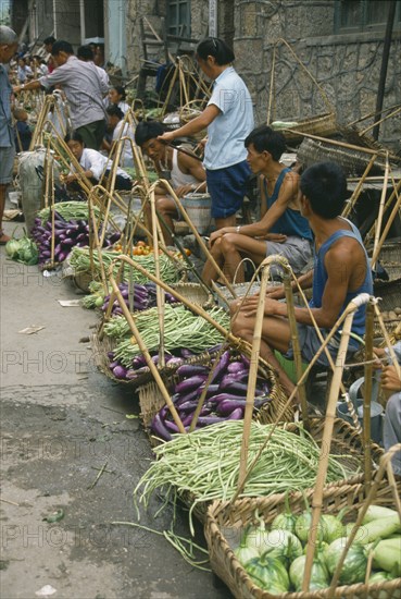 CHINA, Guizhou Province, "Village vegetable market, line of vendors selling beans and aubergines displayed in baskets in front of them."