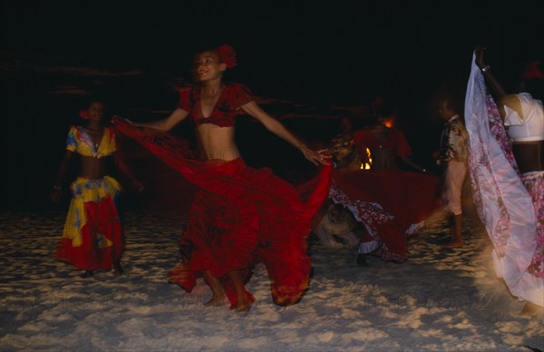 MAURITIUS, Sega Dancers, Women in red costume dancing on the beach at night. Sega is the national dance and music form of Mauritius.