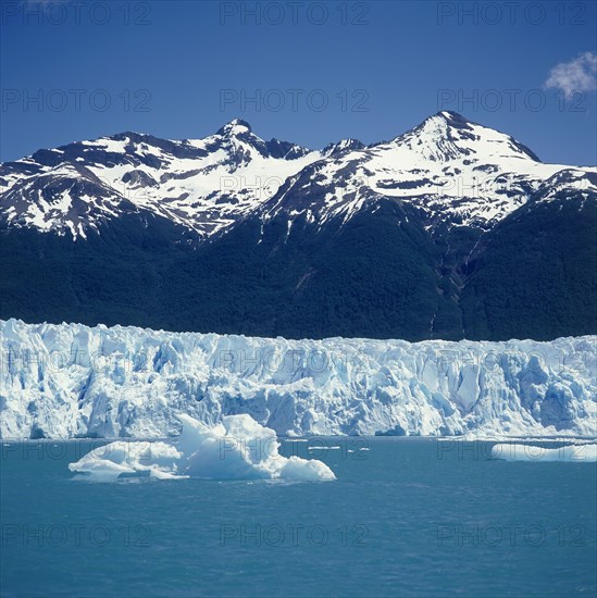 ARGENTINA, Santa Cruz, Parque Nacional Los Glaciares, Moreno Glacier below snow capped mountains with icebergs on Lago Argentian in typical Patagonian landscape