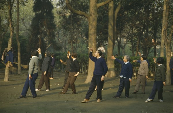 CHINA, Sichuan Province, Chengdu, Group exercise in park at dawn.