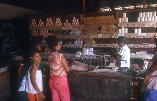 CUBA, Guantanamo Province, Paso de Toa, General Store with store person and customers standing at counter with weighing scales on