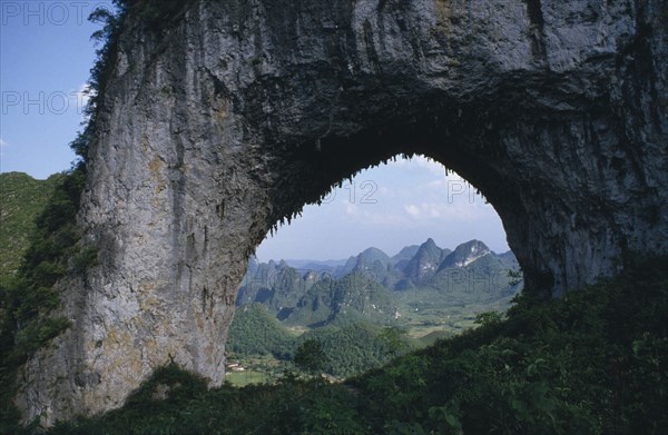 CHINA, Guangxi, Near Guilin, View through natural rock archway near the Li River framing mountainous landscape beyond
