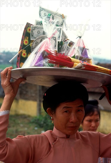 VIETNAM, Den Ba Chua Kho , Woman carrying a display of temple offerings and money on her head
