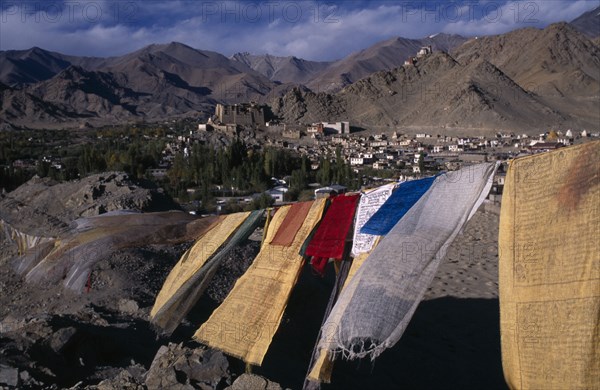 INDIA, Ladakh , Leh , View over Leh Valley and town from hill-top with line of prayer flags flying in wind in foreground.