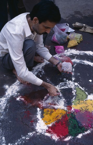 INDIA, Delhi , Painting patterns on ground as base for bonfire during Hindu Holi Festival.
