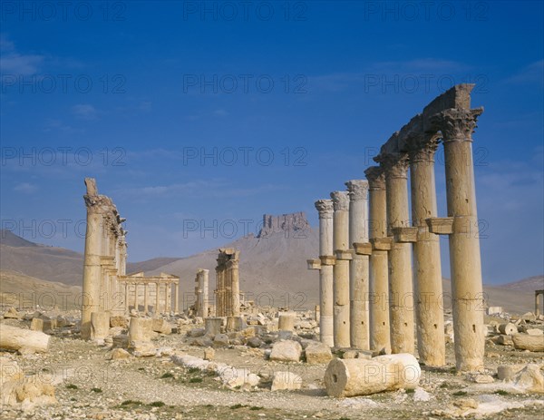 SYRIA, Central, Tadmur, "Monumental Arch, columns and fallen masonry with fort on hillside beyond. "