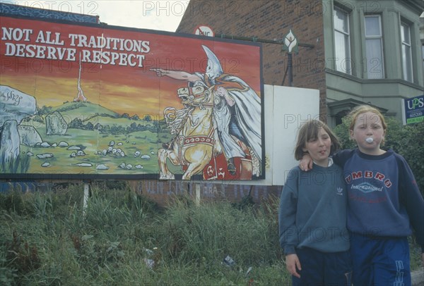 POLITICS, North, Belfast, Nationalist mural with young girls stood next with one girl blowing bubblegum