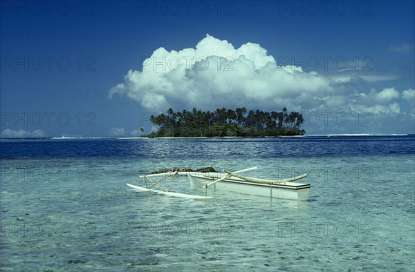 PACIFIC ISLANDS, Tahiti Moorea, Outrigger boat in clear sparkling water and Motu with large white cloud above.