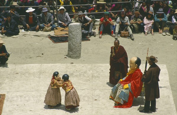 TIBET, Samye Monastery, Clowns performing at a Full Moon Festival with onlookers.