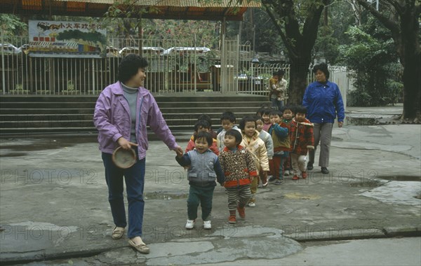 CHINA, Guangzhou , Children, Line of nursery school children with teachers on outing to park.