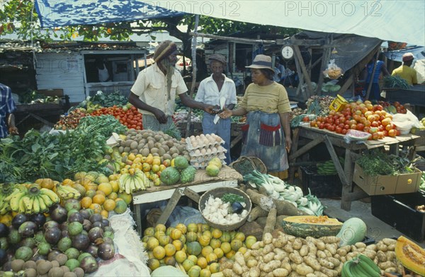 WEST INDIES, Jamaica, Montego Bay, Two women buying fruit from vendor in market