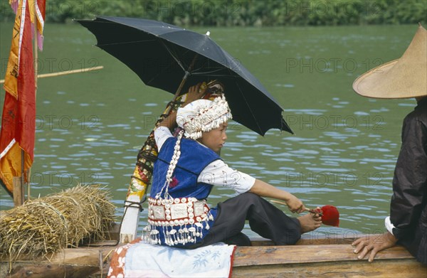 CHINA, Guizhou Province, Festival, Young boy in costume sitting under umbrella on dragon boat during festival