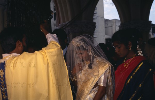 INDIA, Karnataka, Bangalore , "Christian wedding ceremony, bride and groom receiving blessing from priest."