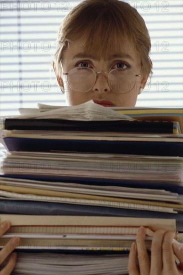 INDUSTRY, Office, Paperwork, Female office worker holding a large bundle of paperwork in her arms