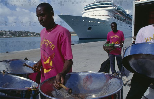 WEST INDIES, Antigua, St Johns, The Halcyon Cove Steel Band playing on quayside with cruise ship behind.
