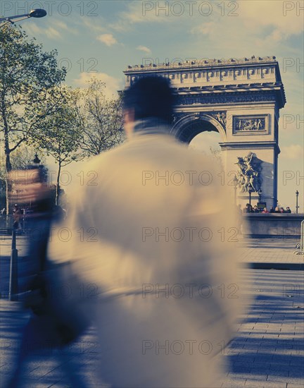 FRANCE, Ile de France, Paris, "Arc de Triomphe with people, blurred in action on the street in the foreground. "