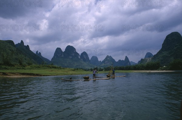 CHINA, Guangxi, Guilin, Cormorant fishermen on rafts on the River Li with limestone karst mountains in the distance