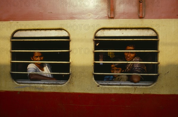 INDIA, Kerala, Cochin, Passengers at barred windows of train carriage.