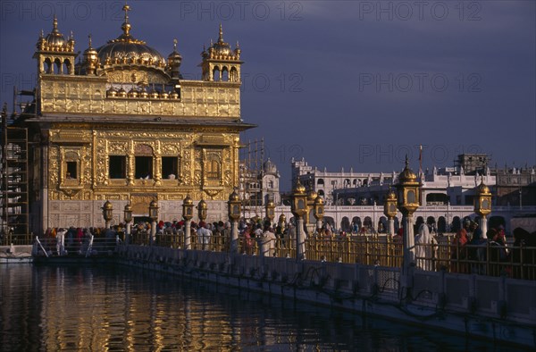 INDIA, Punjab, Amritsar, The Sikh Golden Temple with people on the walkway across the water