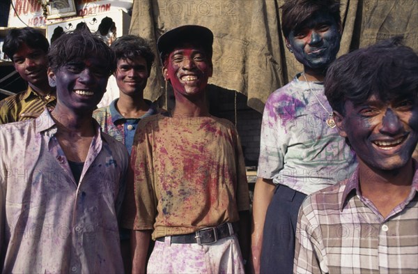 INDIA, Delhi , Group of young men with their faces covered with coloured powder paint dyes during Holi Festival