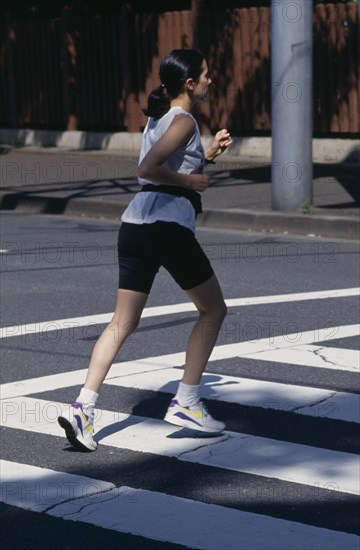 10051308 SPORT Jogging Female jogger on pedestrian crossing.