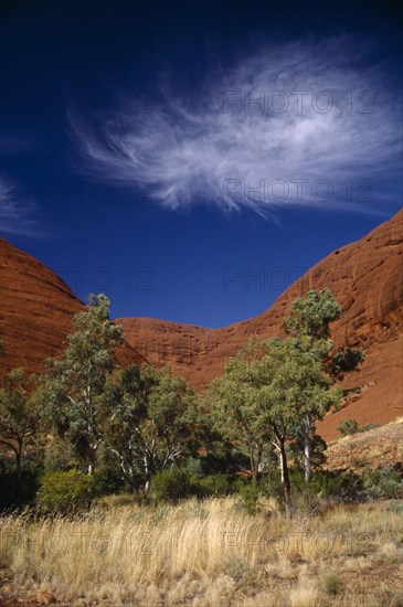 AUSTRALIA, Northern Territory, The Olgas, "Also known as Katatjuta, meaning Many Heads. Large red rocks with trees in front and whispy white clouds in the sky above"