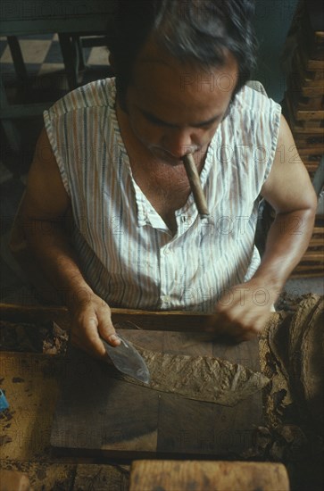 CUBA, Sancti Spiritus, Trinidad, Man smoking a cigar whilst he rolls cigars in a cigar factory