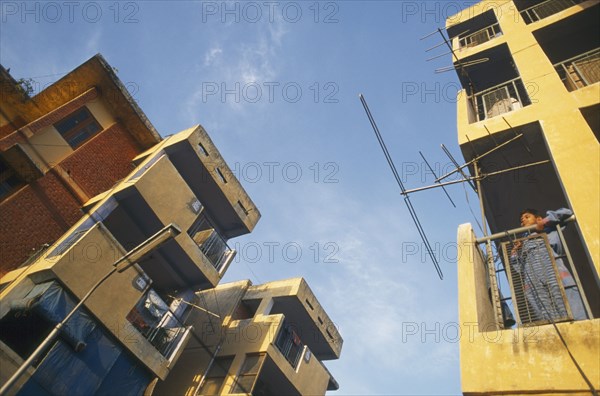 INDIA, Uttar Pradesh , Delhi, New housing estate. View looking up at buildings with boy standing on a balcony