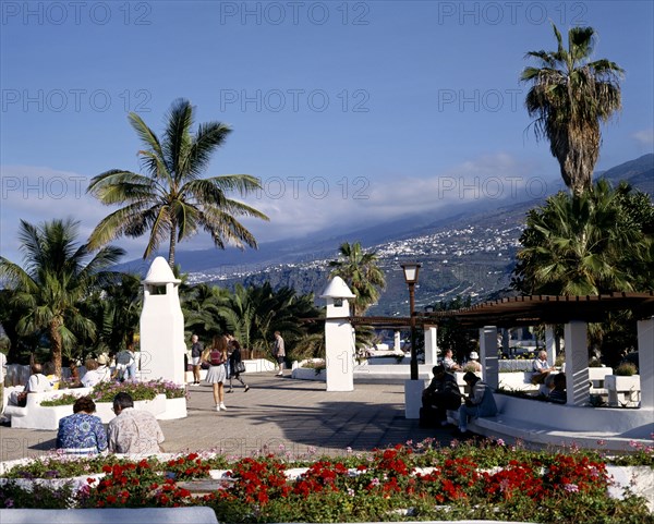 SPAIN, Canary Islands, Tenerife, "Promenade,whitewashed walls,wooden sunshades,flowers,people,hills "