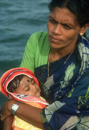 SRI LANKA, People, Woman holding baby in her arms. Traditionally dressed and wearing modern wrist watch