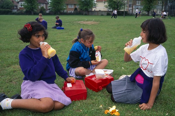 EDUCATION, School, Children, Kids eating packed lunches in the playground.