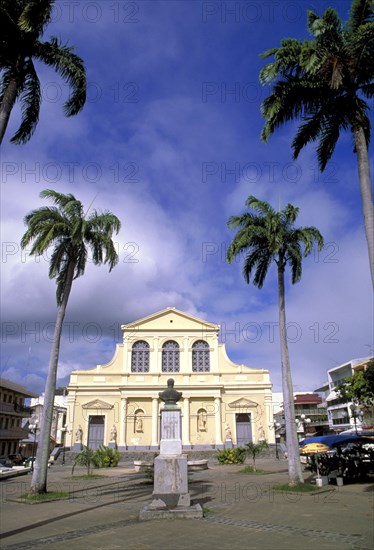 WEST INDIES, Guadeloupe, Grande-Terre, Church in small square in Pointe-a-Pitre with coconut palm trees and a bust in front
