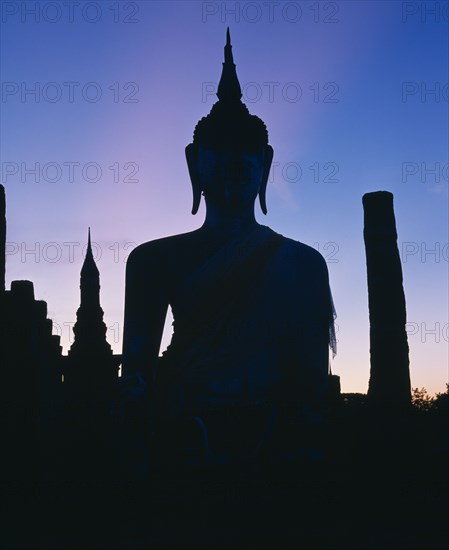 THAILAND, Central Plains, Sukhothai, Silhouette of buddha on temple - pink mauve sky