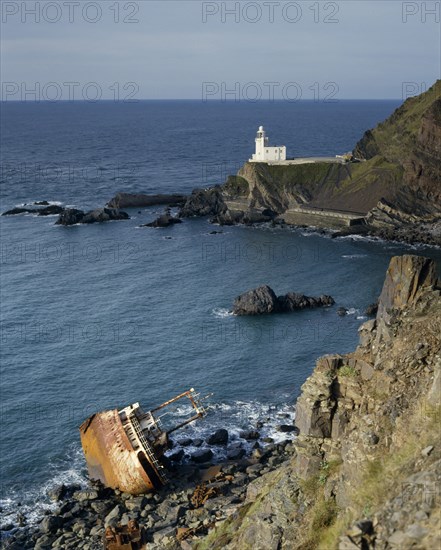 ENGLAND, Devon, North Devon-Hartland Point lighthouse next to rugged coast with a shipwrecked boat