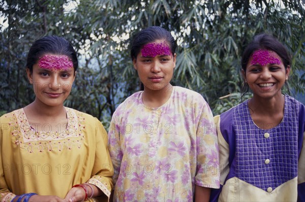 INDIA, Sikkim , Tashiding, Three young women with coloured rice on their foreheads for Diwali.  Three-quarter portrait.