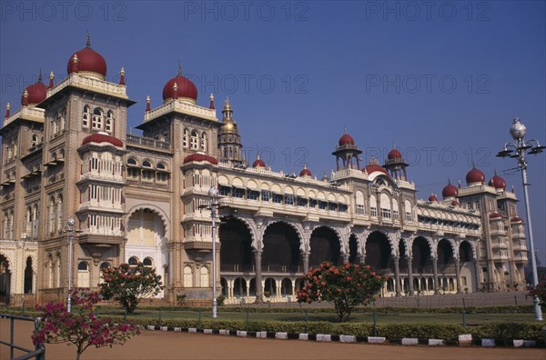 INDIA, Karnataka, Mysore , Mysore Palace also known as Amba Vilas Palace completed in 1912 in Indo-Saracencic style.  Exterior with flowering bushes.