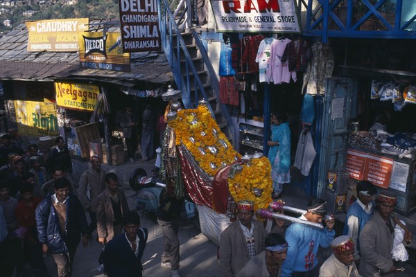 INDIA, Himachal Pradesh, Kulu, Figures of temple gods garlanded with flowers being carried through street during Hindu Dussehra festival.