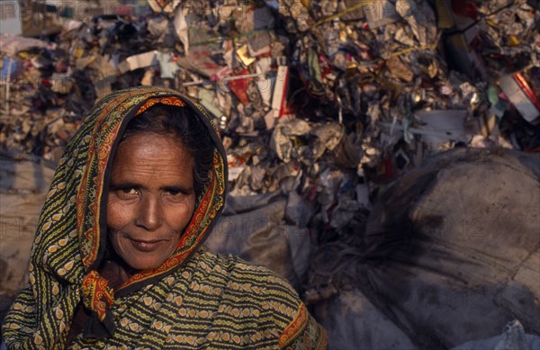 10038590 INDIA  Delhi Female rubbish recycler.  Head and shoulders portrait with rubbish tip behind.