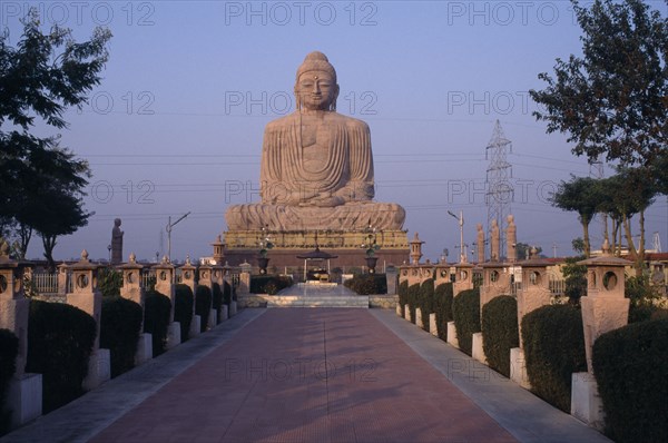 INDIA, Bihar, Bodh Gaya, Giant seated Buddha statue seen from pathway leading up to the base.