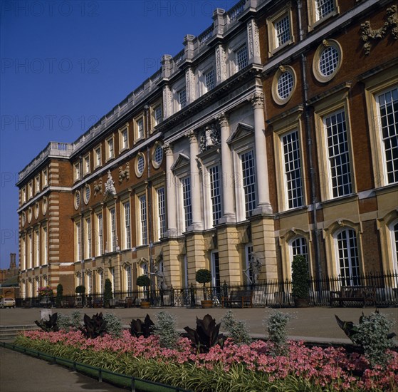 ENGLAND, London, Hampton Court Palace.  Angled view of exterior over     flower borders