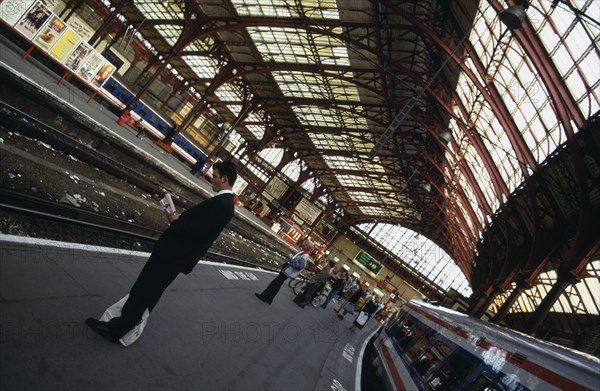 TRANSPORT, Rail, Station, Railway station with angled view of passengers waiting on empty platform and part view of glass and iron Victorian roof. Brighton East Sussex England