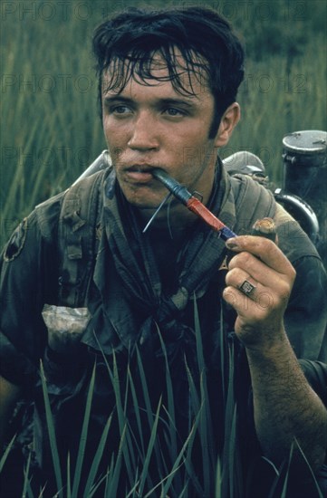 VIETNAM, War, 1968, 9th Division soldier near Tan An sitting in a rice paddy smoking Cambodian Red in a pipe