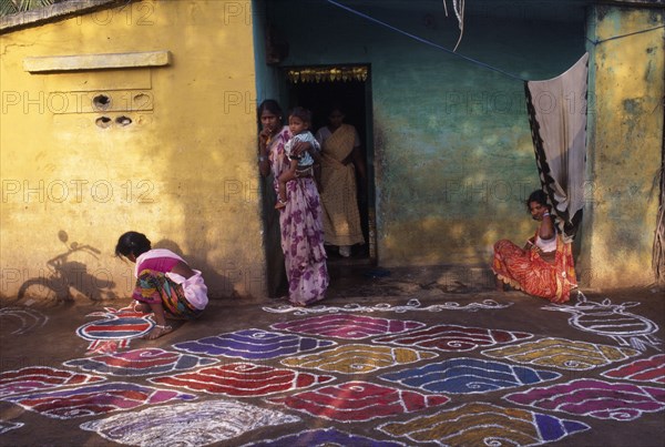 INDIA, Tamil Nadu, Festivals, Pongal festival marking the end of harvest and lasting four days. Women painting decorative pattern on ground outside home.